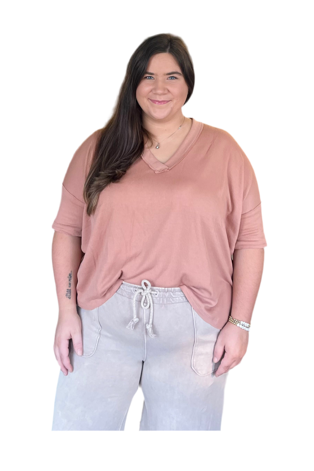 Woman wearing clay shirt and tan lounge pants on a white background