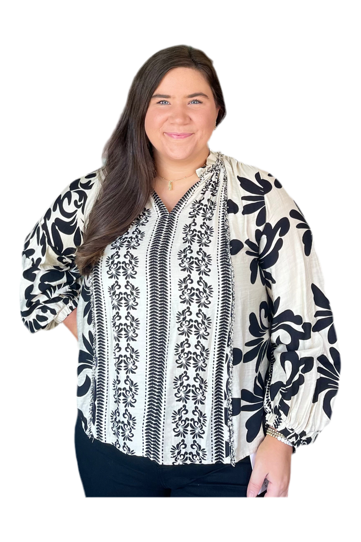 Woman wearing a black and white floral patterned blouse on a white background