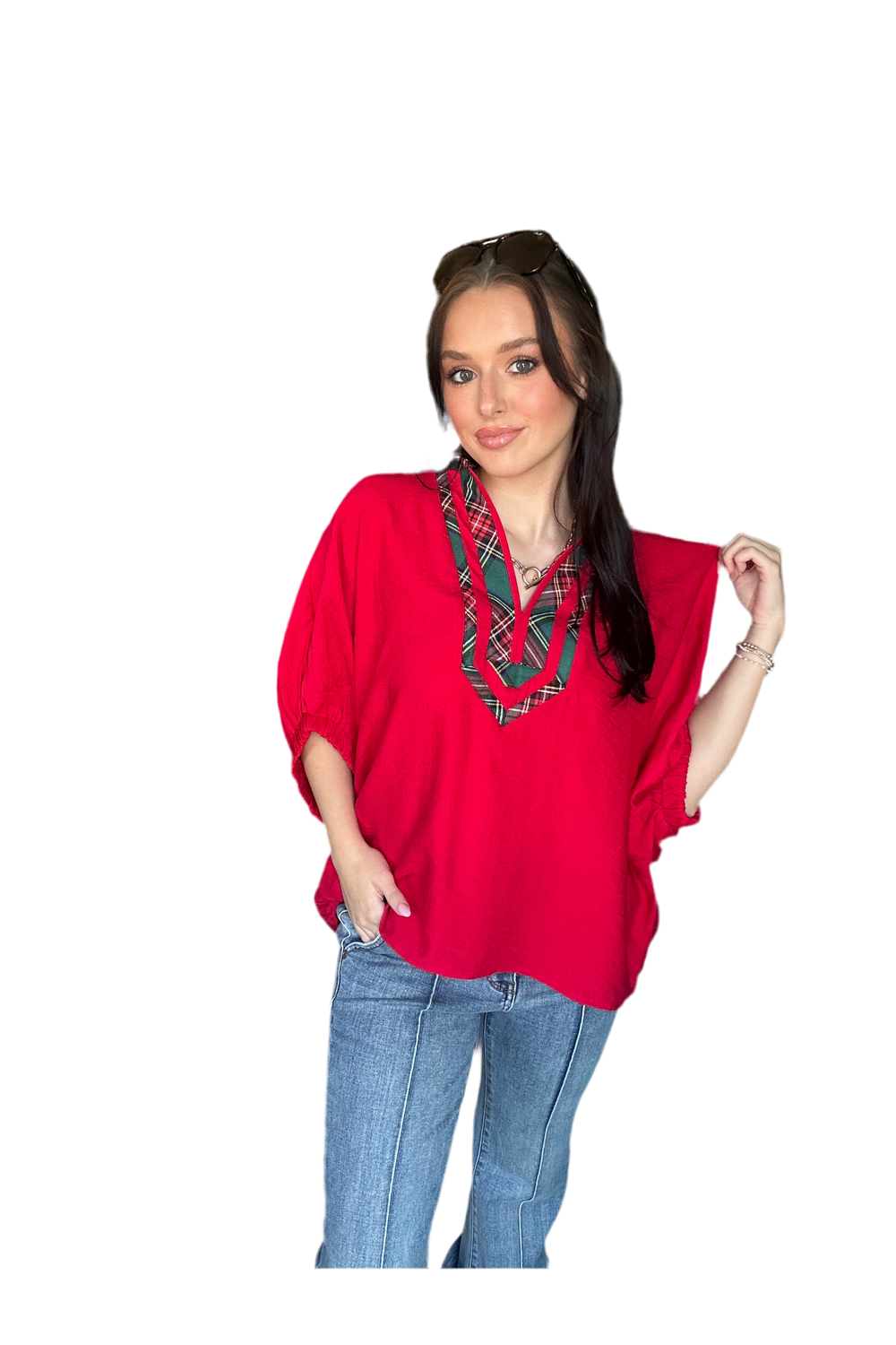 Woman wearing a red blouse with plaid details and blue jeans on a white background