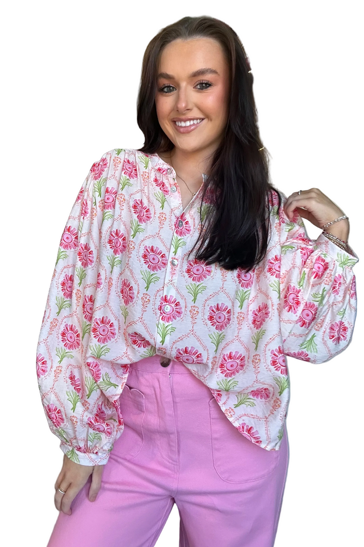 Woman wearing a floral blouse and pink pants on a white background