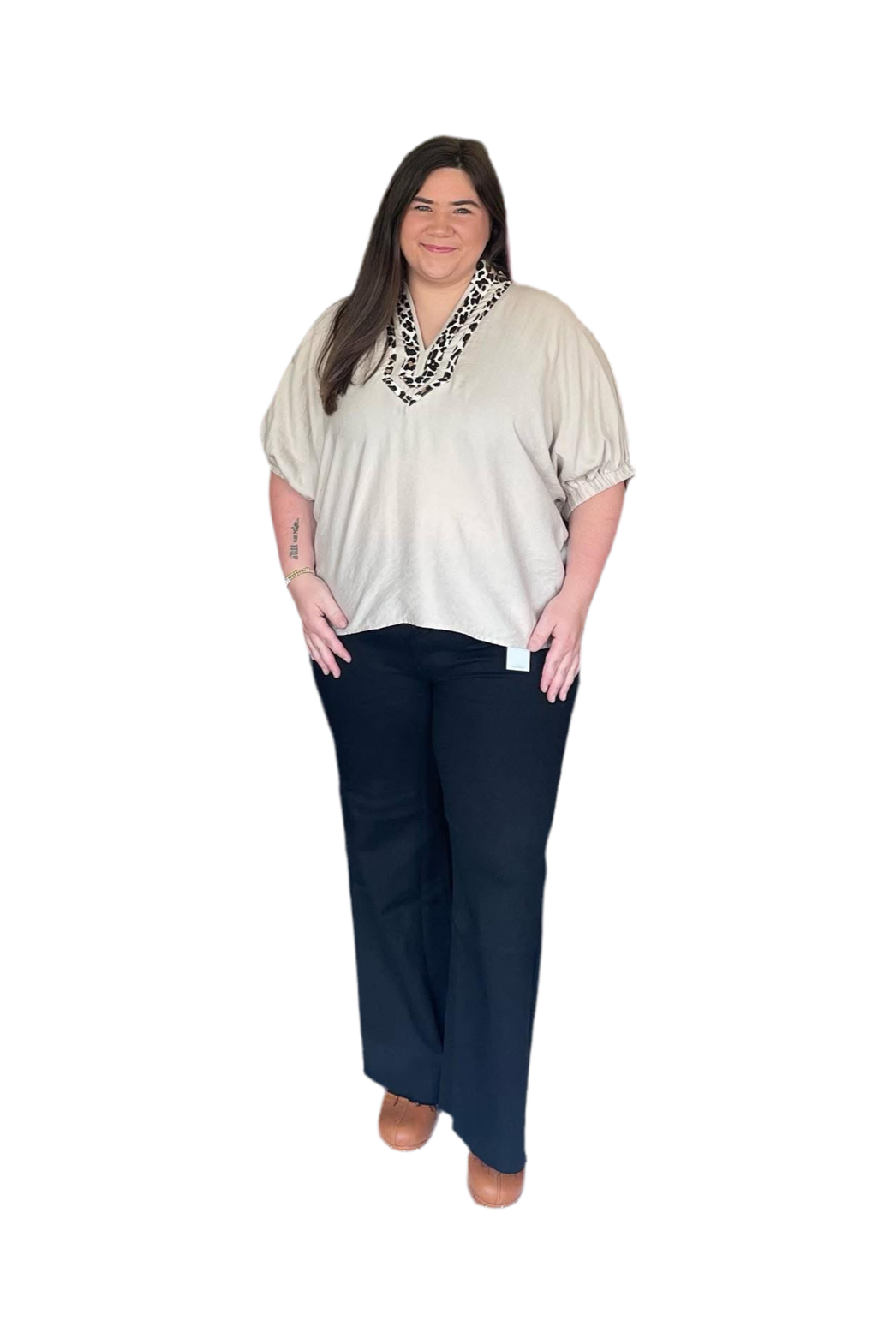 Woman wearing a beige top with lace neckline and navy pants on a white background