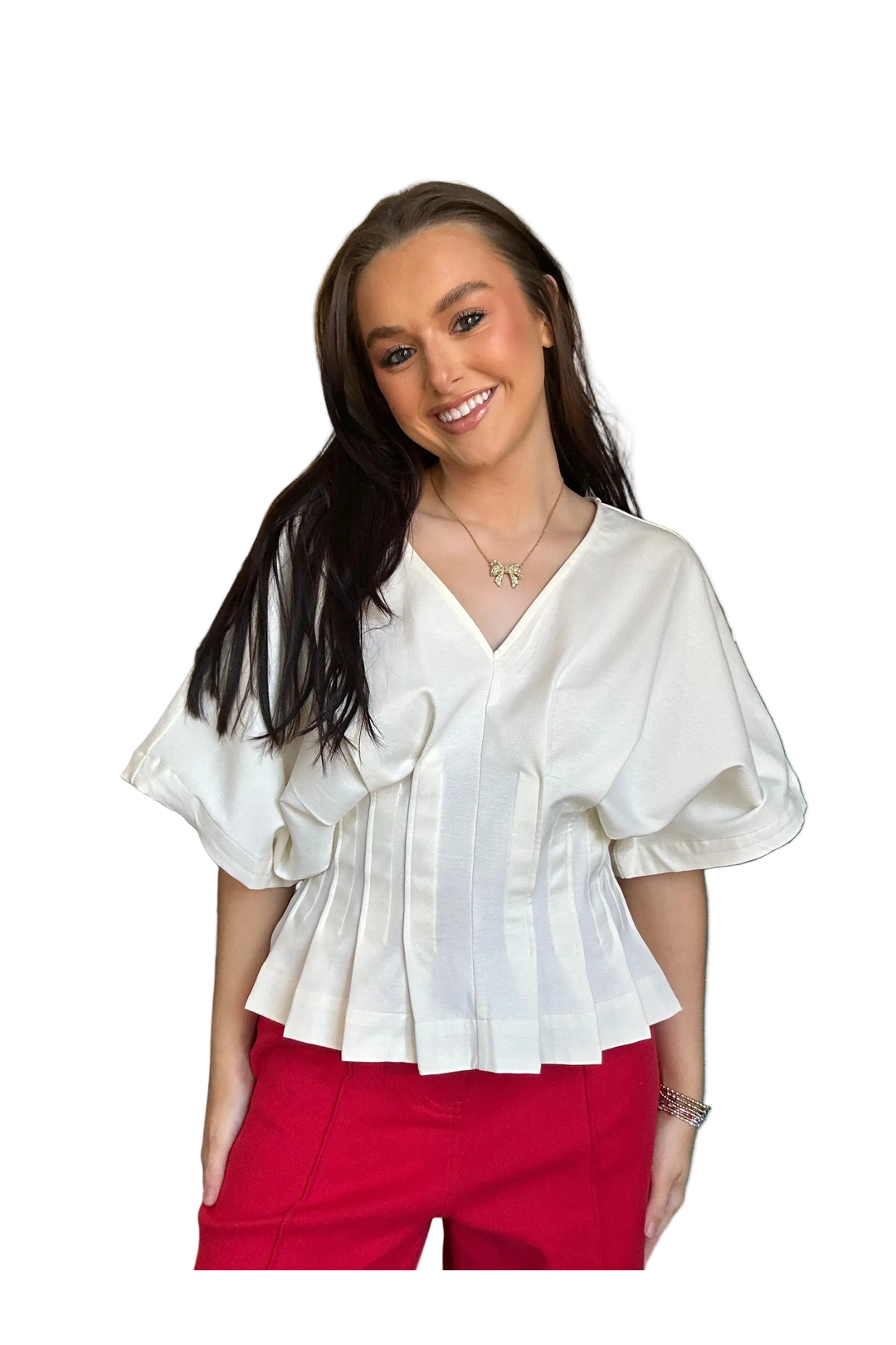 Woman wearing a white blouse with ruffled sleeves and red pants on a white background