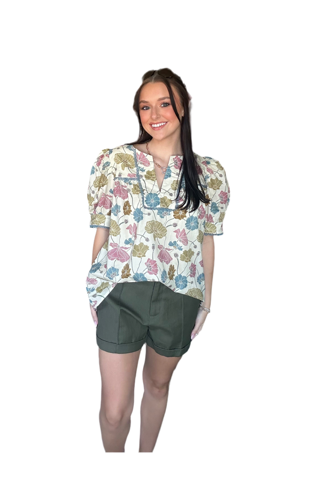 Woman wearing a floral blouse and green shorts on a white background