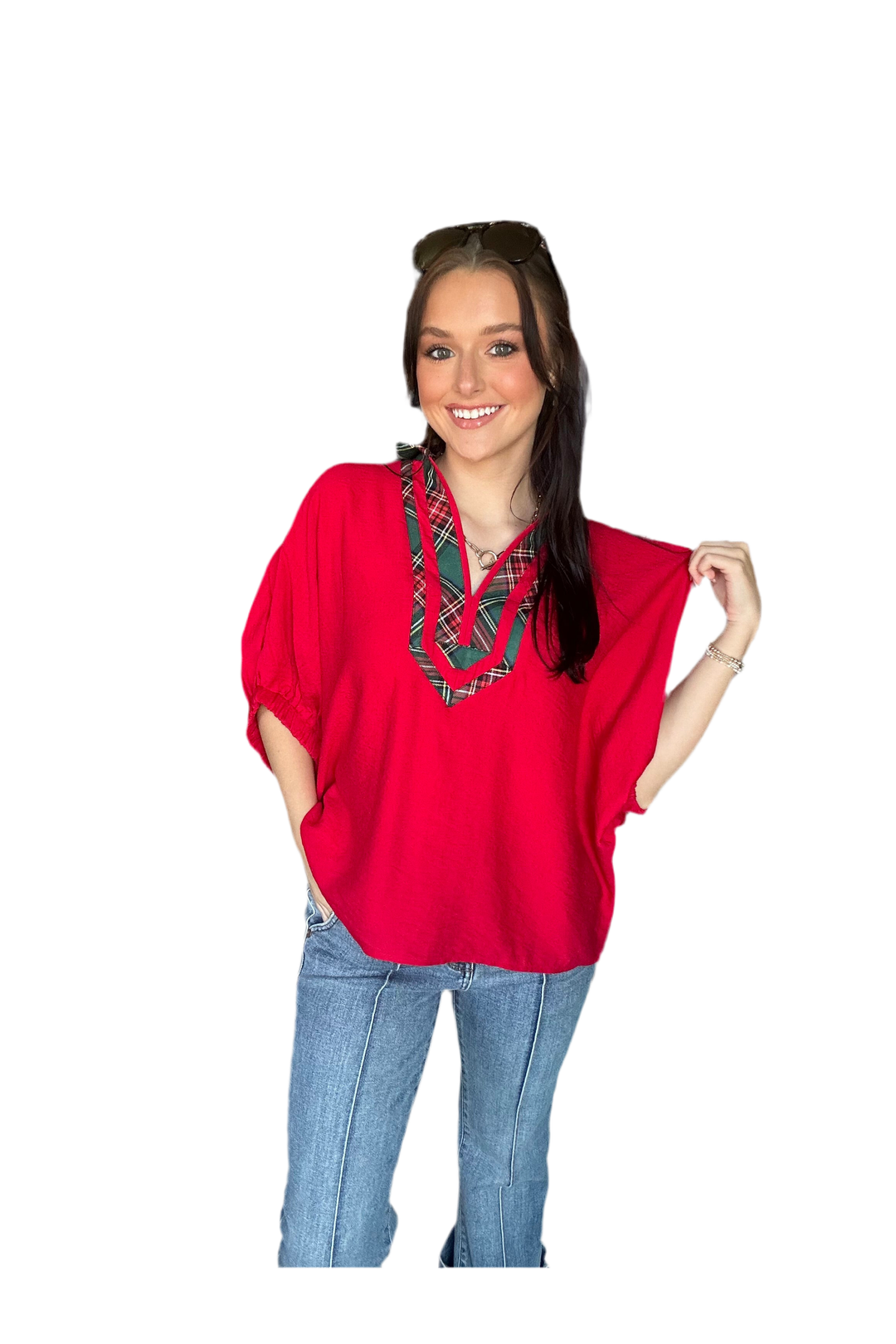 Woman wearing a red top with a plaid pattern and blue jeans on a white background