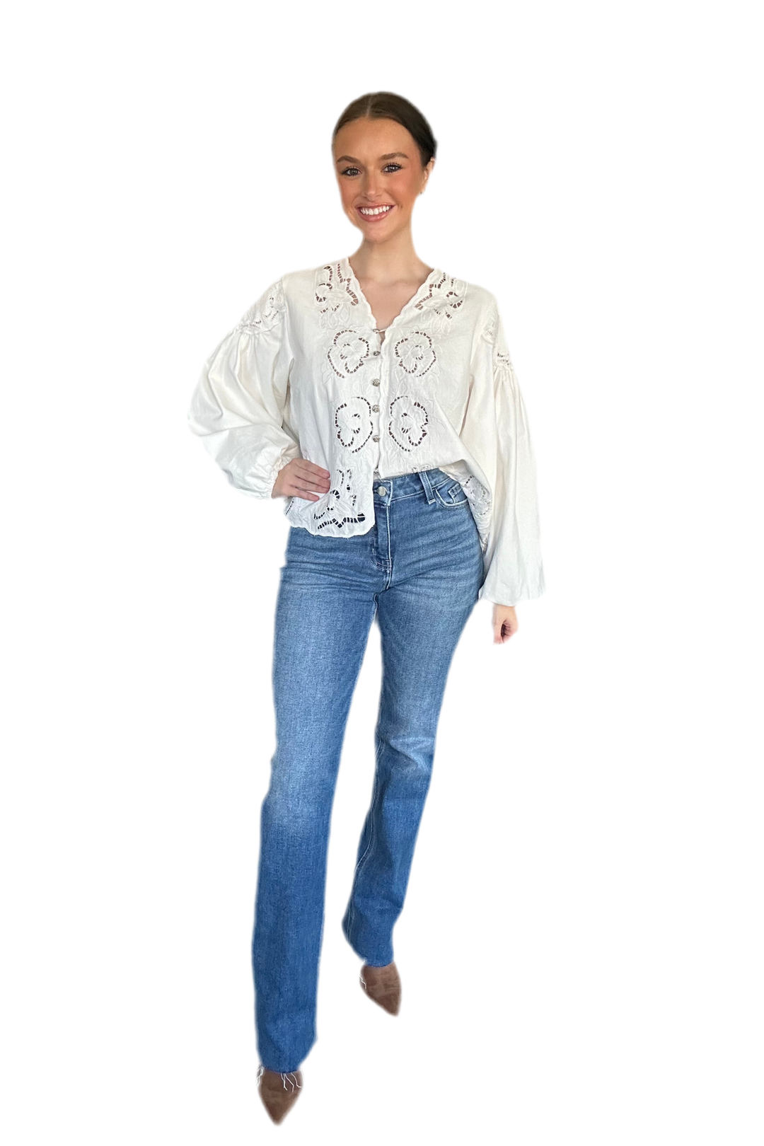 Woman wearing a white blouse with lace details and blue jeans on a white background
