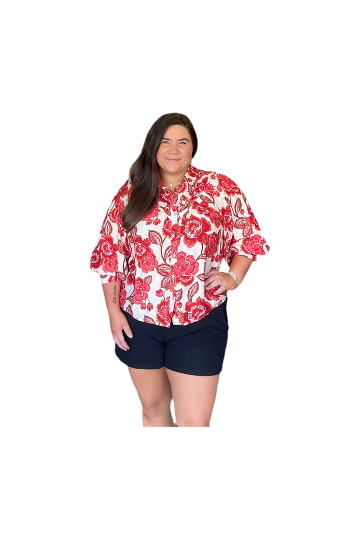 Woman wearing a red floral shirt and navy shorts on a white background