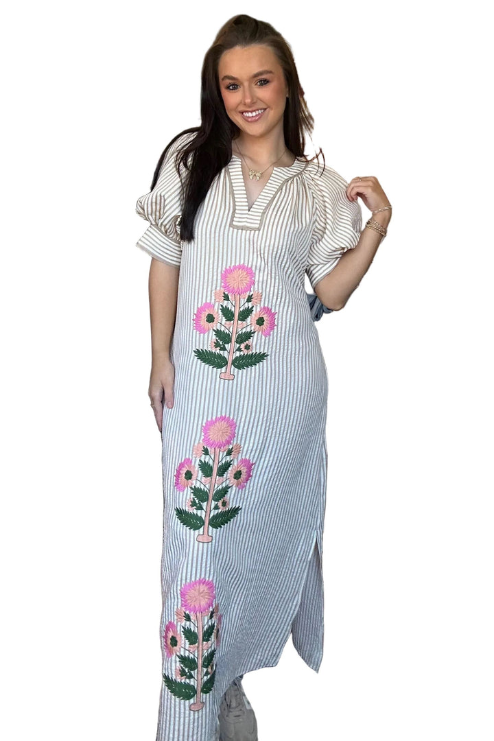 Woman wearing a long, light-colored dress with floral patterns on a white background