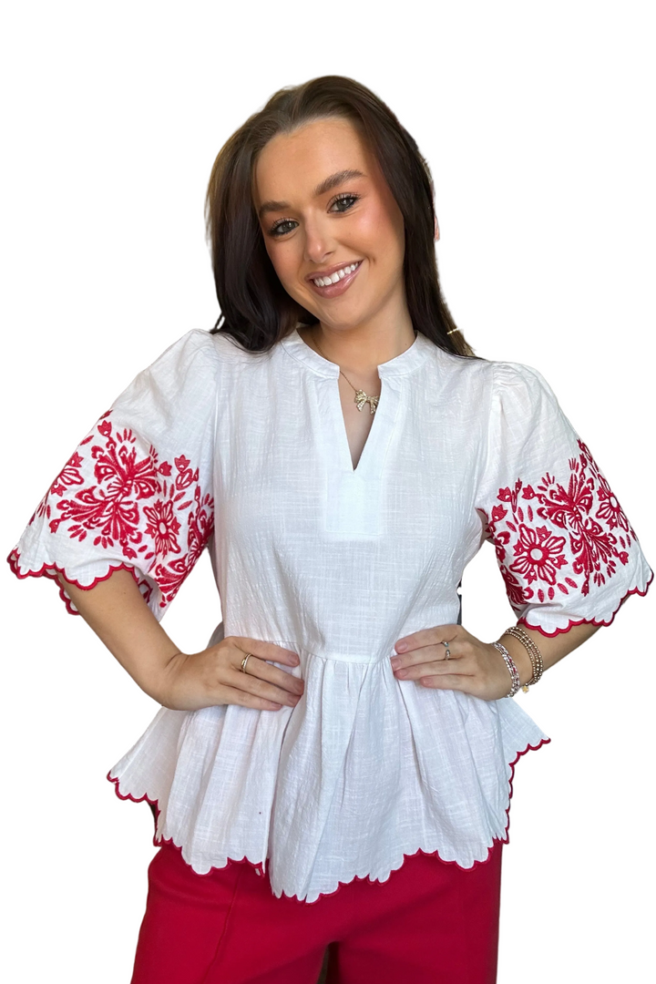 Woman wearing a white blouse with red floral patterns on a white background