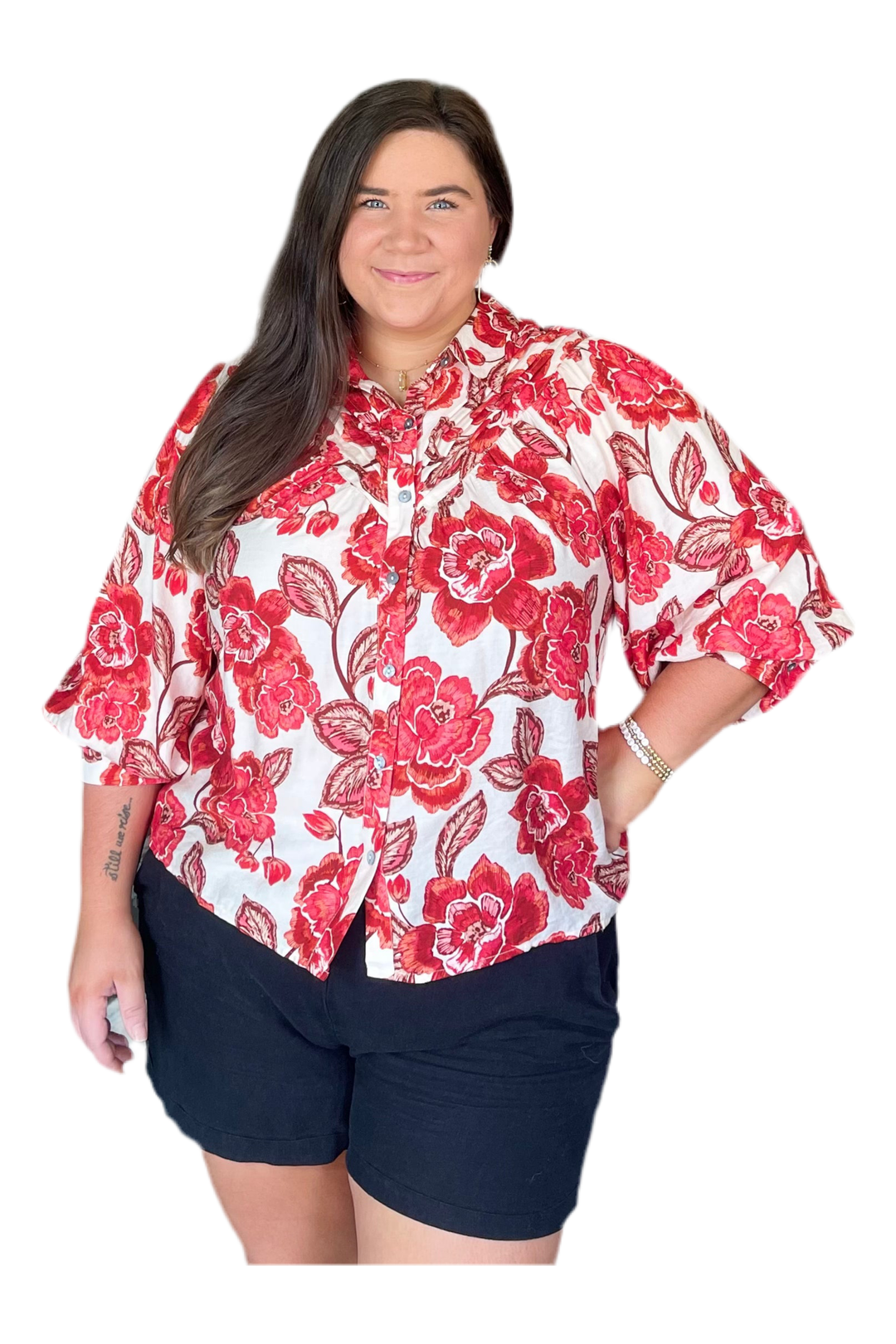Woman wearing a red floral blouse and navy shorts on a white background