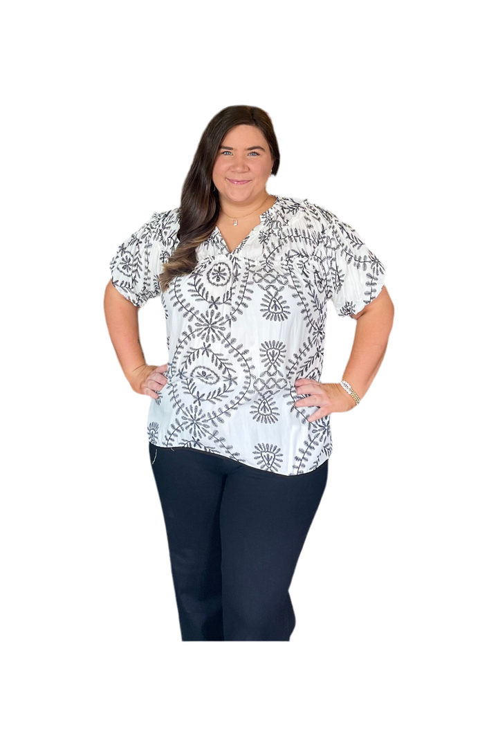 Woman wearing a white blouse with black patterns on a white background