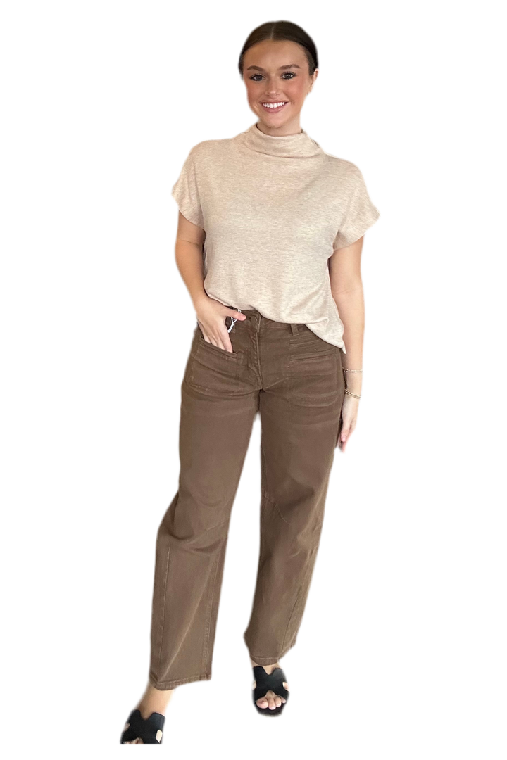 Woman wearing a beige top and brown pants on a white background