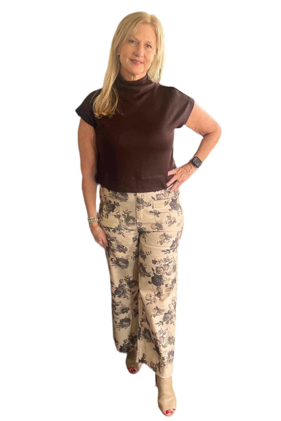 Woman wearing a brown top and floral pants on a white background