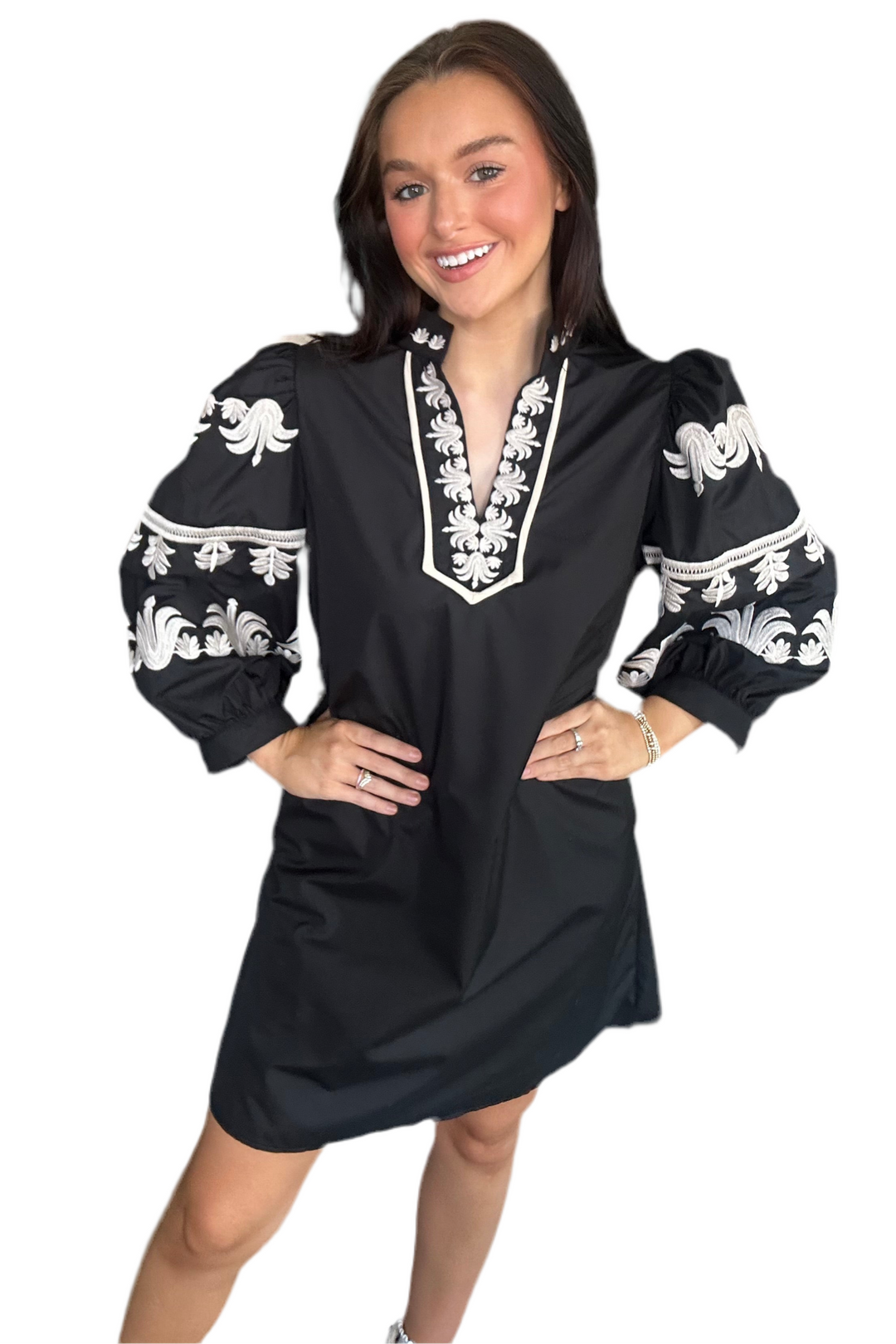 Woman wearing a black dress with white embroidery on a white background