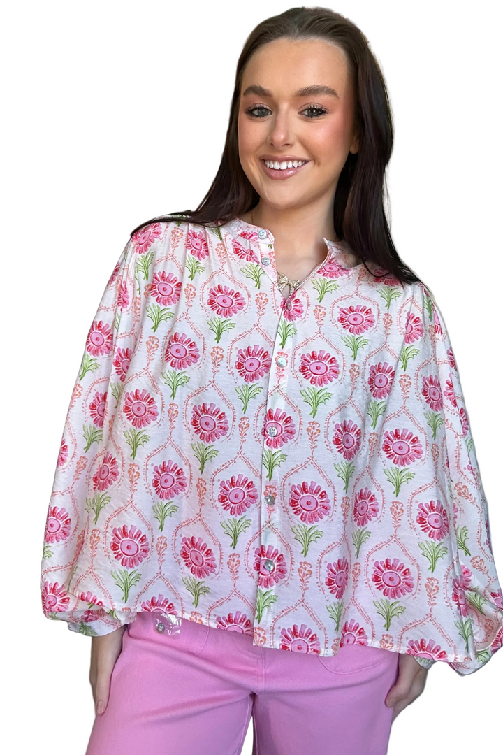 Woman wearing a floral blouse and pink pants on a white background