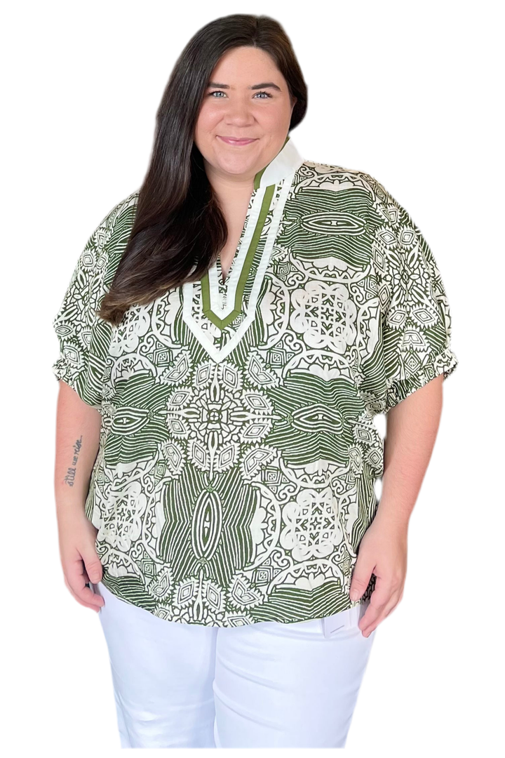 Woman wearing a green and white patterned blouse on a white background