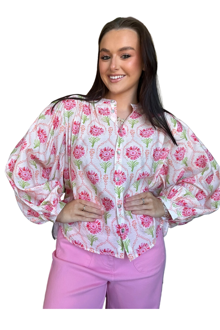 Woman wearing a floral blouse and pink pants on a white background