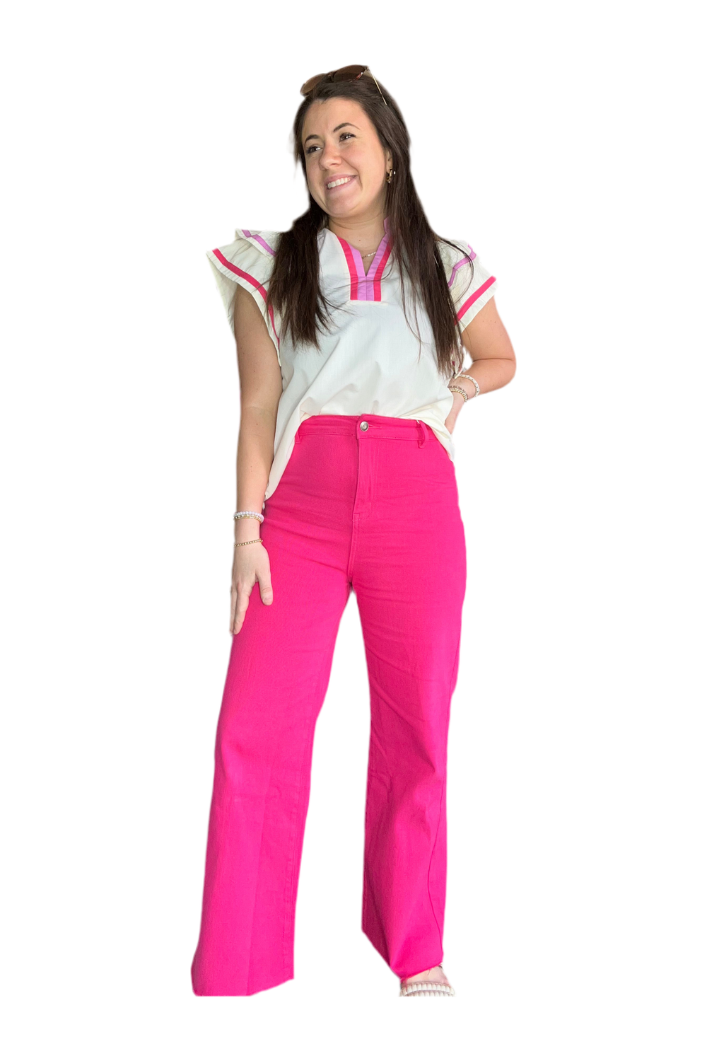 Woman wearing a white top with pink trim and bright pink pants on a white background.
