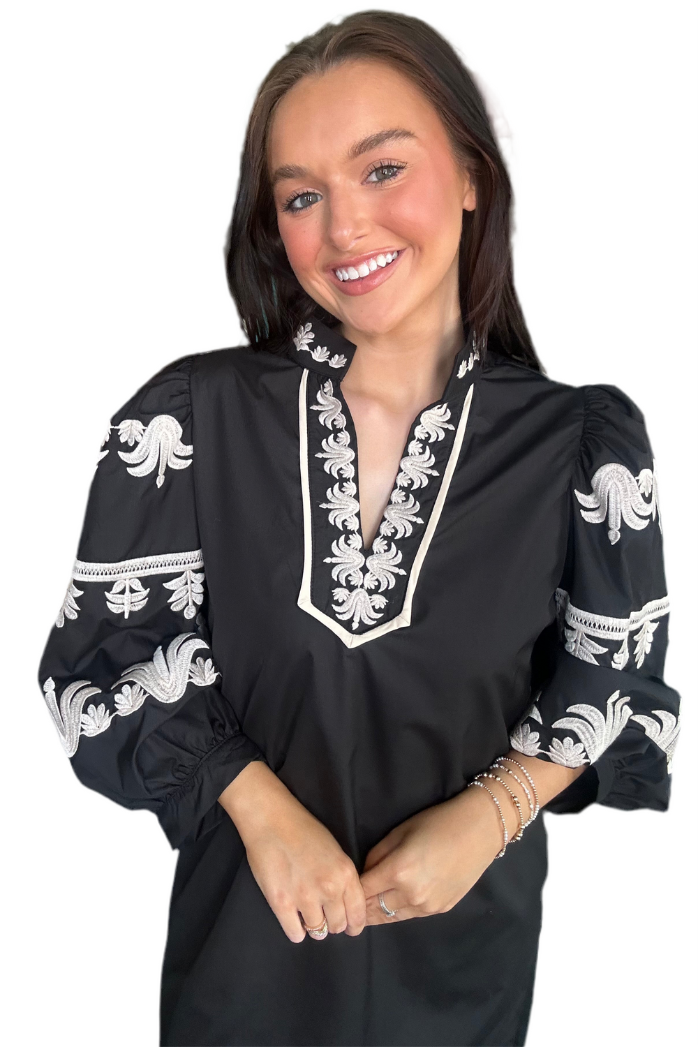 Woman wearing a black dress with white embroidery on a white background