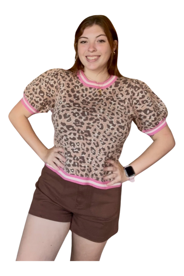 Woman wearing a leopard print top with pink trim and brown shorts on a white background