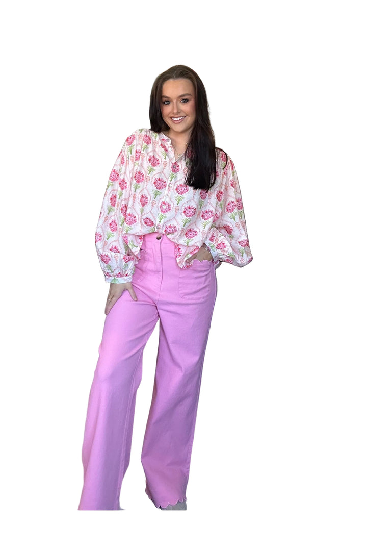 Woman wearing a floral blouse and pink pants on a white background
