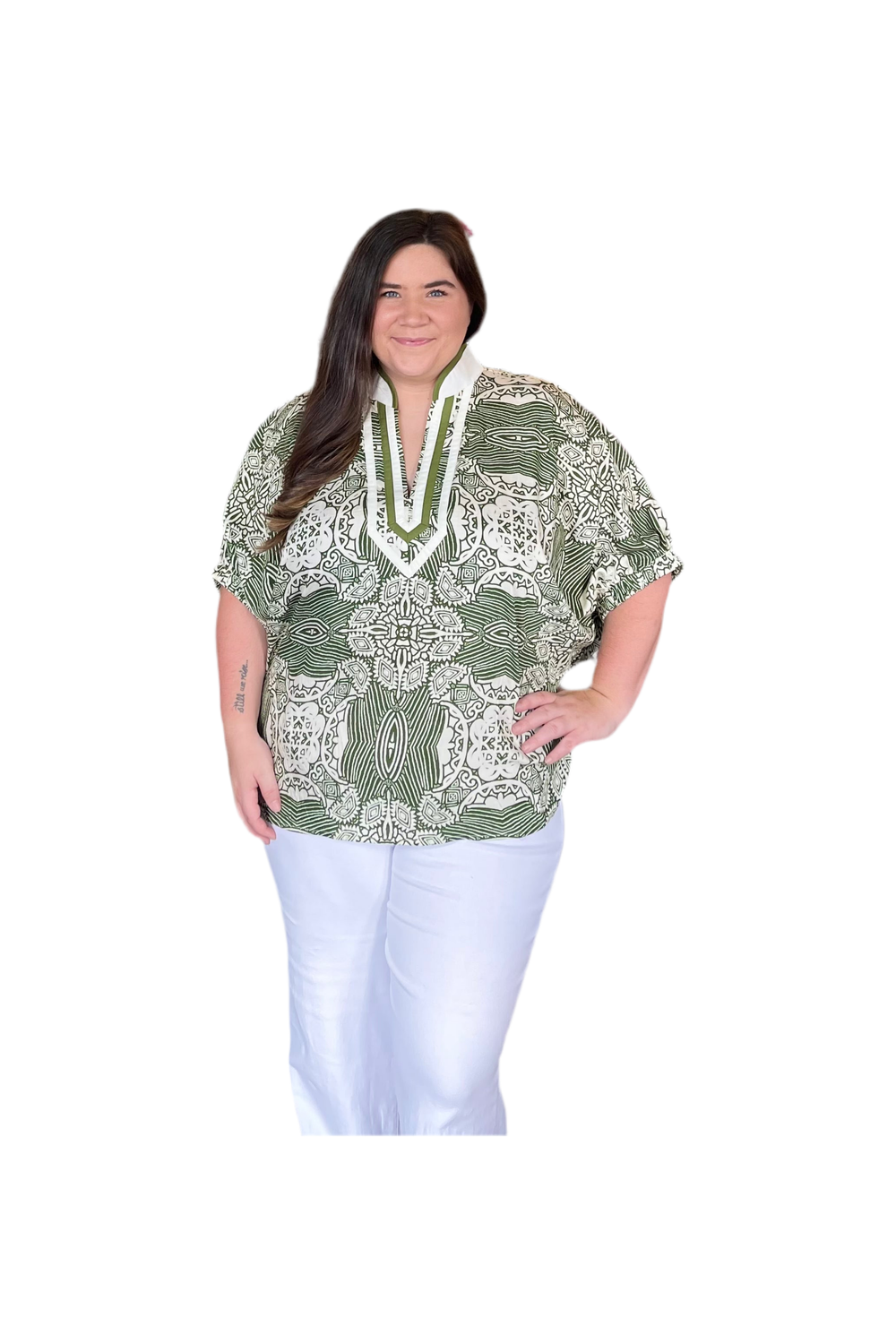 Woman wearing a green patterned blouse with white pants on a white background