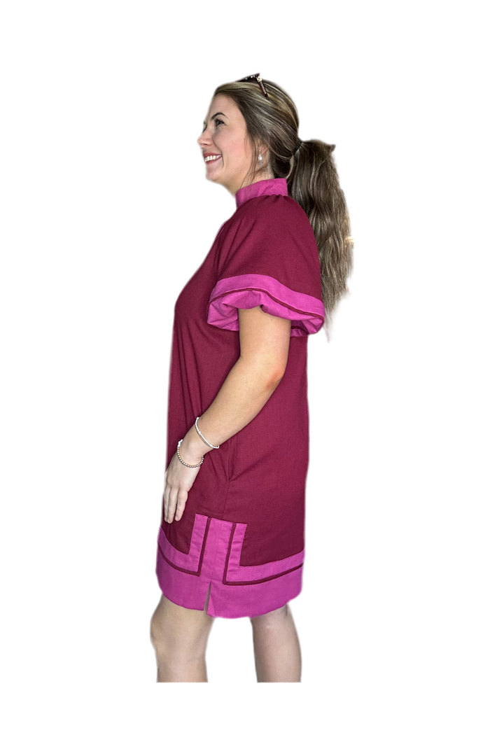 Woman wearing a maroon dress with pink accents on a white background
