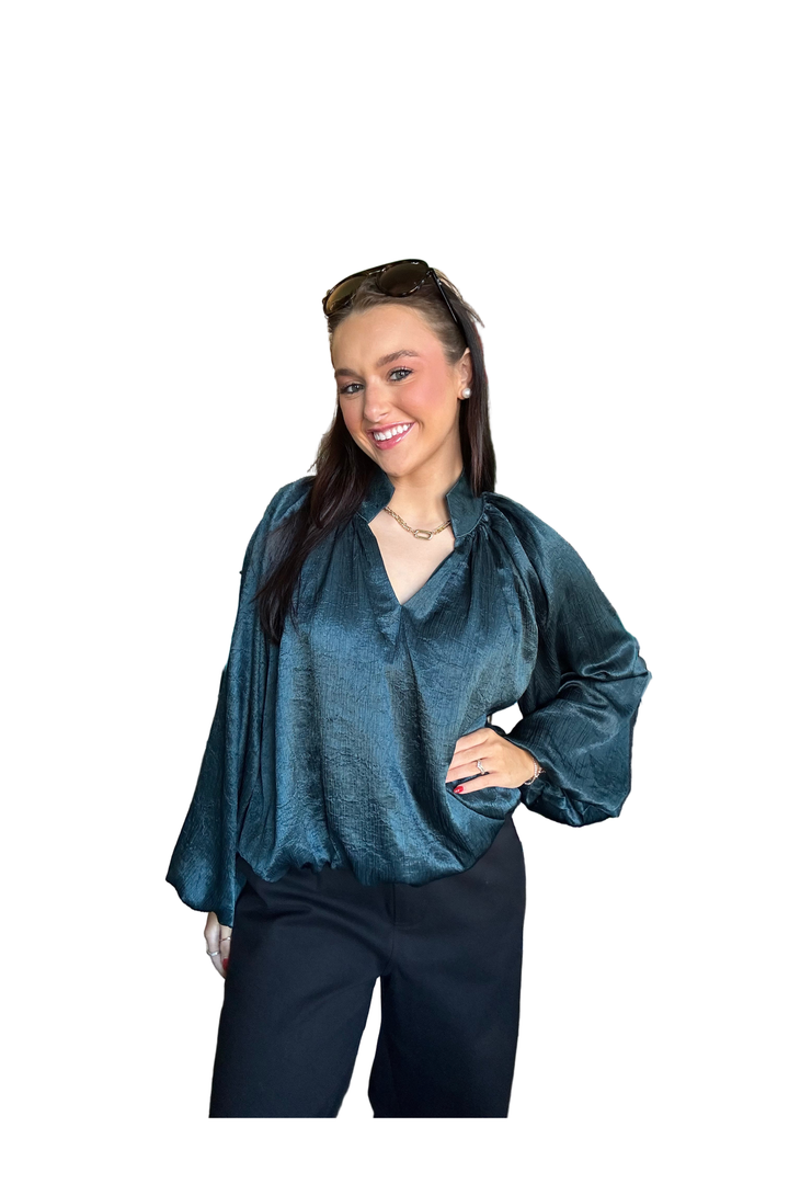 Woman wearing a hunter green long sleeve bubble blouse 