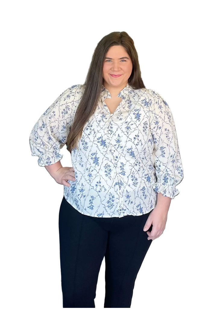 Woman wearing a floral blouse and dark pants on a white background