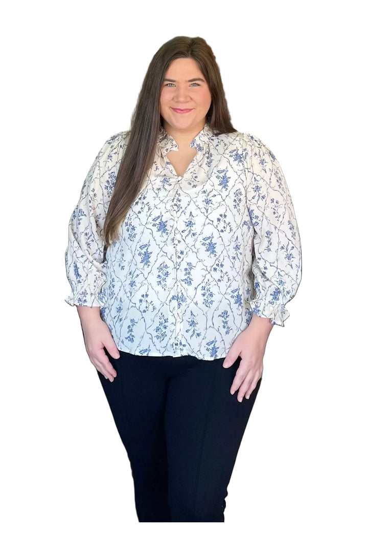 Woman wearing a floral blouse and dark pants on a white background