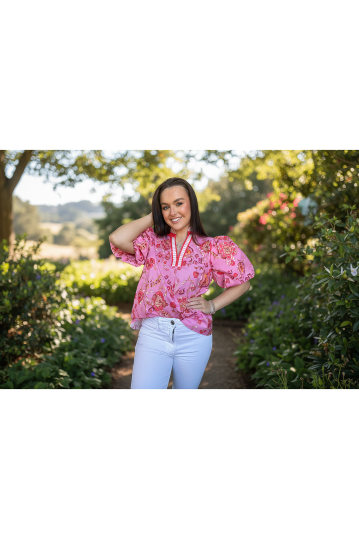 Woman wearing a pink floral blouse with puffed sleeves on a white background